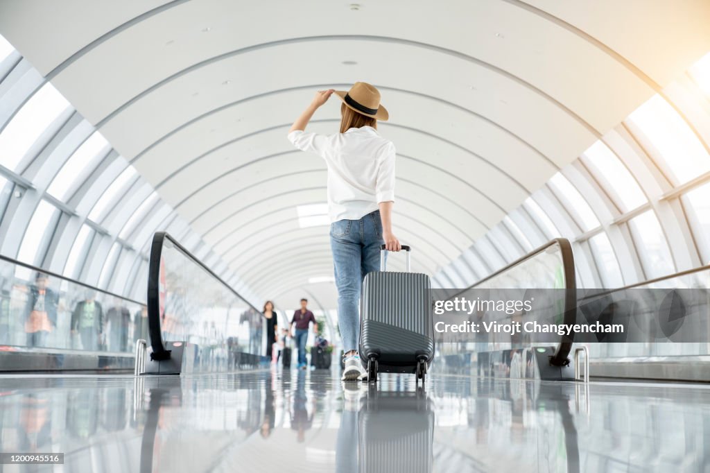 Young woman wearing casual clothes and walking in the airport hall