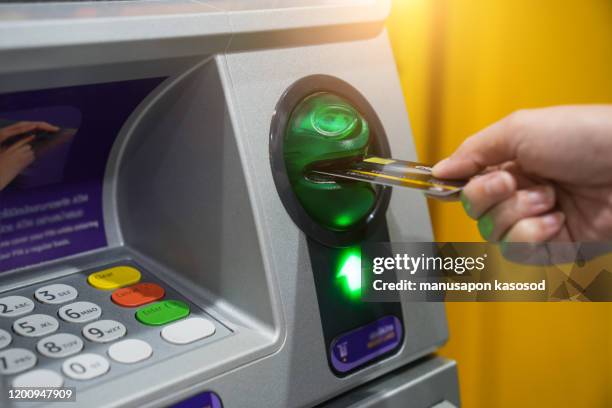 woman hand is inserting card to atm machine to withdraw or transfer money - cajero automático fotografías e imágenes de stock