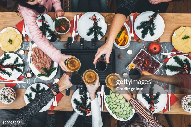 dinig de famille à la table en bois avec le gril de raclette - cheese stock photos et images de collection