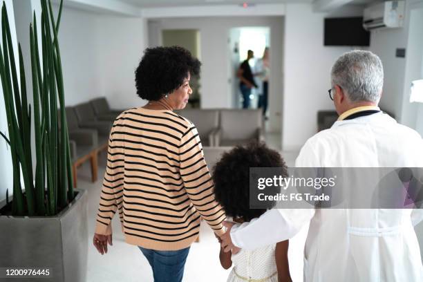 hogere arts die met een familie (moeder en dochter) bij het ziekenhuis loopt - screening of child of grace arrivals stockfoto's en -beelden