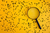 Magnifying With Wooden Alphabets Around On Yellow Background