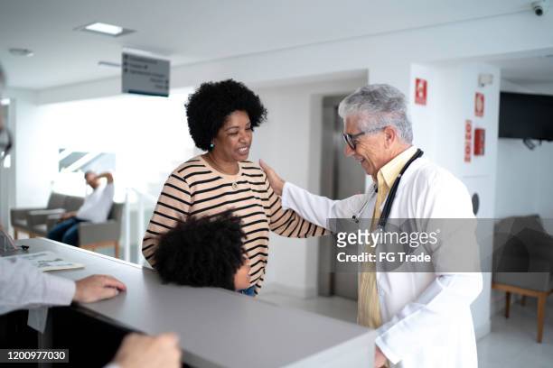 senior doctor welcoming / greeting a family (mother and daughter) at hospital - dignity elderly stock pictures, royalty-free photos & images