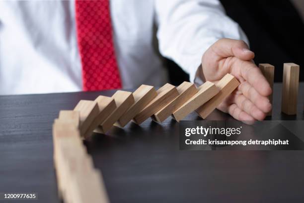 businessman stop domino effect. risk management and insurance concept - risk management stock pictures, royalty-free photos & images