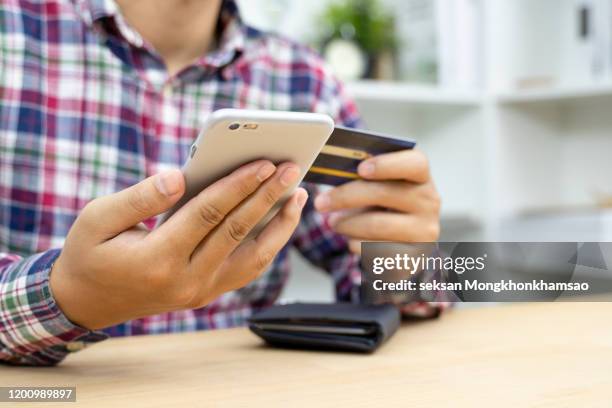 young man hands holding credit card and using phone - corporate crime stock pictures, royalty-free photos & images