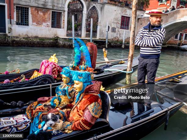 een buitengewone paar maskers op een traditionele gondel tijdens het carnaval van venetië - gondola traditional boat stockfoto's en -beelden