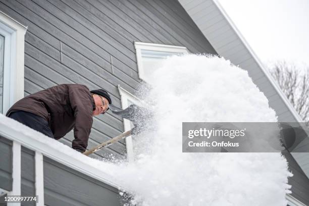 senior man shoveling snow in winter after snowstorm - winter snow shovel stock pictures, royalty-free photos & images