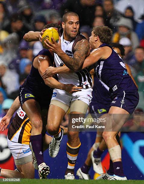 Lance Franklin of the Hawks looks to break from a tackle by Alex Silvagni and Stephen Hill of the Dockers during the round 19 AFL match between the...