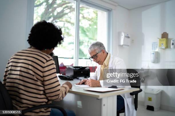 male doctor writing prescription to her patient - doctor writing prescription for patient stock pictures, royalty-free photos & images