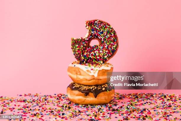 three donuts, one with bite - doughnuts stockfoto's en -beelden