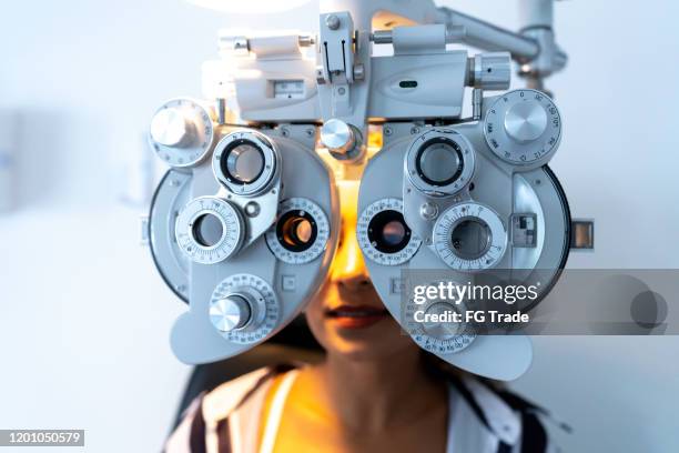 women doing eyesight measurement with optical phoropter in ophthalmology clinic - phoropter stock pictures, royalty-free photos & images