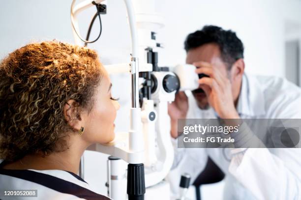 mature doctor examining patient doing eyesight measurement in ophthalmology clinic - ophthalmologist stock pictures, royalty-free photos & images