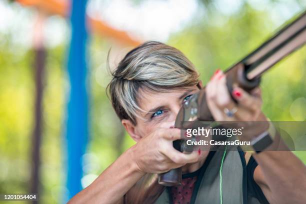 porträt der fokussierten erwachsenen frau ziel mit pistole auf shooting range - stockfoto - tontaubenschießen stock-fotos und bilder
