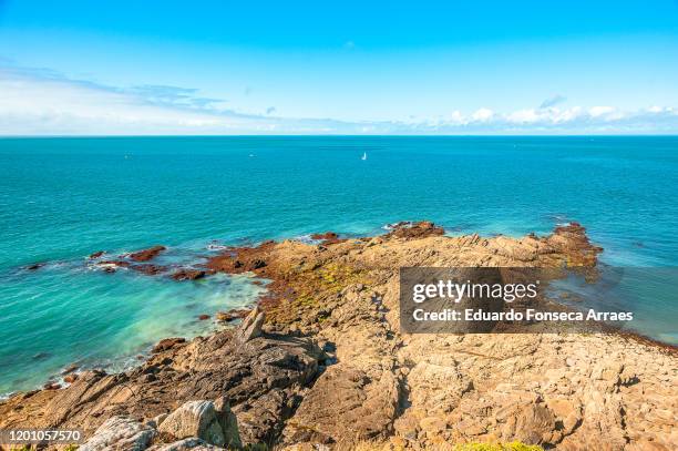 view of the ocean / sea, the coastal features, the turquoise water and rocks at pointe du grouin on the coast of bretagne against a sunny clear blue sky - cancale fotografías e imágenes de stock