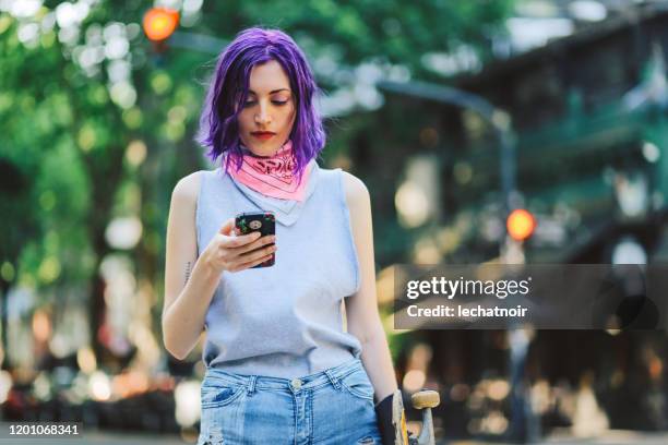 chica patinadora usando el teléfono en la calle - cabello morado fotografías e imágenes de stock