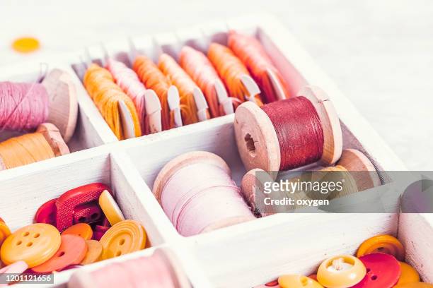 close-up box with sewing set collection of yellow, red, pink spools threads arranged in a white wooden box - nähset stock-fotos und bilder