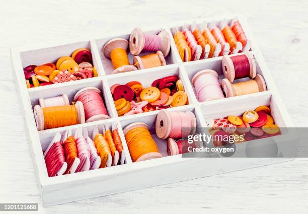 box with sewing set collection of yellow, red, pink spools threads arranged in a white wooden box - button sewing item 個照片及圖片檔