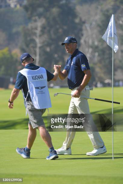 Caddie John Wood and Matt Kuchar bump fist on the seventh green during the third round of the Genesis Invitational at Riviera Country Club on...