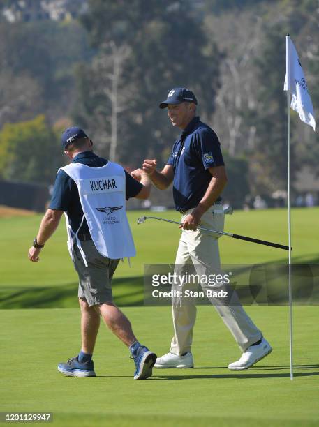 Caddie John Wood and Matt Kuchar bump fist on the seventh green during the third round of the Genesis Invitational at Riviera Country Club on...