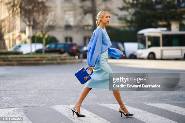 Leonie Hanne wears a blue ruffled top, a pale blue skirt, a blue Lady Dior bag, Dior pointy shoes, during Paris Fashion Week - Haute Couture...