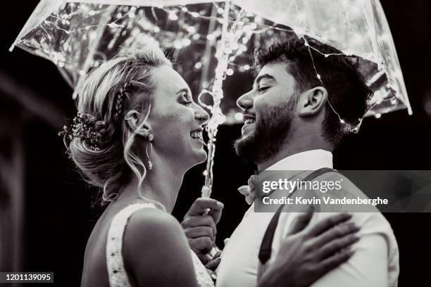 young wedding couple dancing under the fairy umbrella at night - rain kiss stockfoto's en -beelden