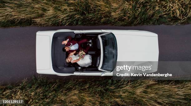 young beautiful wedding couple driving away - bride and groom wedding car stock pictures, royalty-free photos & images