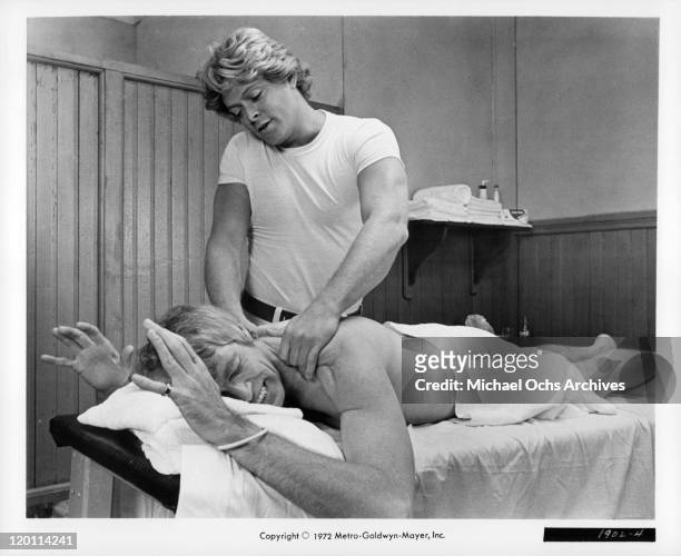 James Coburn gets massage from Michael Blodgett in a scene from the film 'The Carey Treatment', 1972.