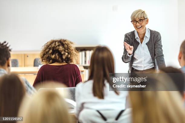 glückliche reife professorin hält einen vortrag vor ihren studenten im hörsaal. - professor stock-fotos und bilder