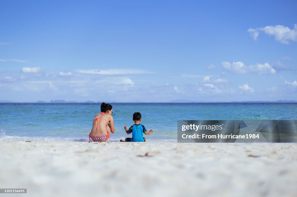 Mom and son enjoying blue sky, crystal clear seawater and white sand on Koh Poda island