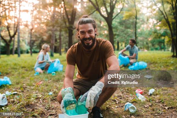 young activist cleaning the park from the garbage - people recycling stock pictures, royalty-free photos & images