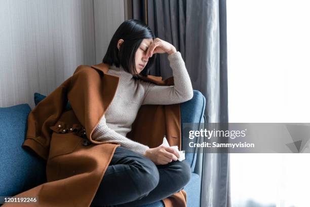 young woman holding her nose while lying on sofa at home - sinus stock pictures, royalty-free photos & images