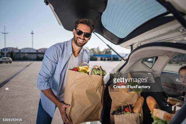 male vegan packing his groceries at car trunk - shopping bags car boot stock pictures, royalty-free photos & images