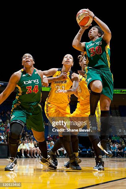 Tanisha Wright drives to the hoop as her teammate Le'coe Willingham of the Seattle Storm holds back Jennifer Lacy and Amber Holt of the Tulsa Shock...