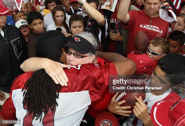 Wide receiver Larry Fitzgerald of the Arizona Cardinals hugs cancer survivor Maureen Hannah of Fountain Hills, Arizona following the team training...