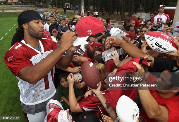 Wide receiver Larry Fitzgerald of the Arizona Cardinals signs autographs for fans following the team training camp at Northern Arizona University on...