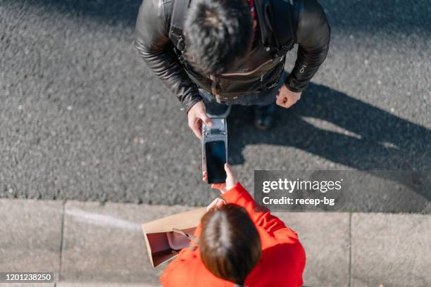 mujer que hace el pago sin contacto por sacar alimentos - pago por móvil fotografías e imágenes de stock