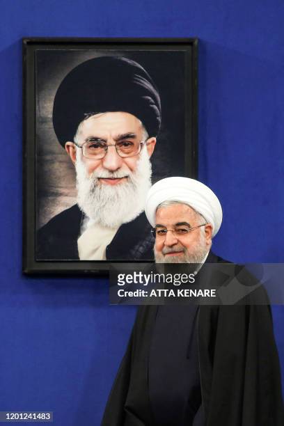 Iranian President Hassan Rouhani walks past a portrait of Supreme Leader Ayatollah Ali Khamenei as he arrives for a news conference in the capital...