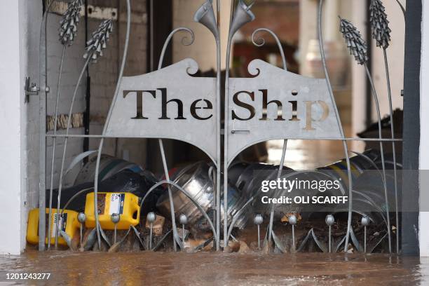 Kegs of beer float in floodwater from the overflowing River Teme inside the gates of the Ship public house in Tenbury Wells, western England, on...