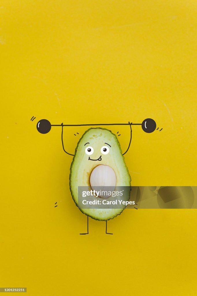 Funny avocado charactert with dumbbells at gym