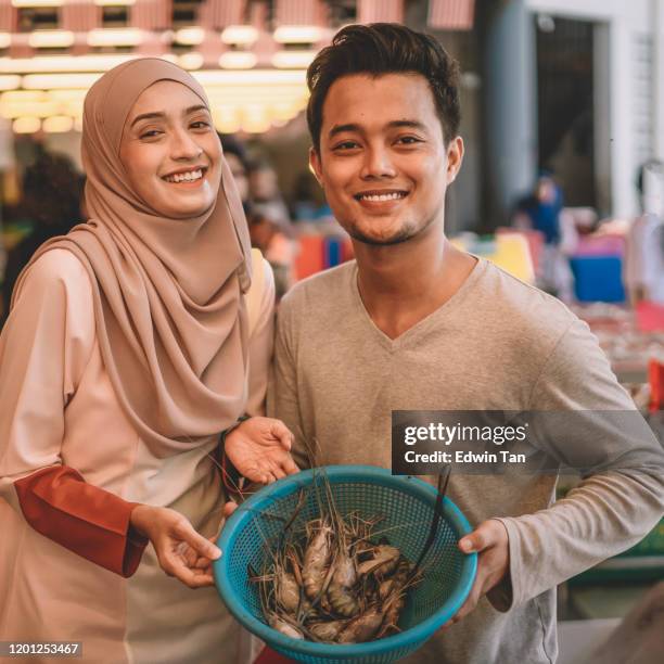an asian malay couple buying fish from the fish stall in wet market during weekend selecting fish from the shelf - malay lover stock pictures, royalty-free photos & images