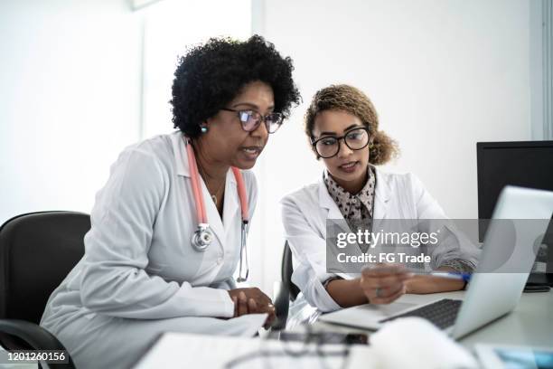 vrouwelijke artsen die laptop gebruiken tijdens conferentie/vergadering - two doctors talking stockfoto's en -beelden