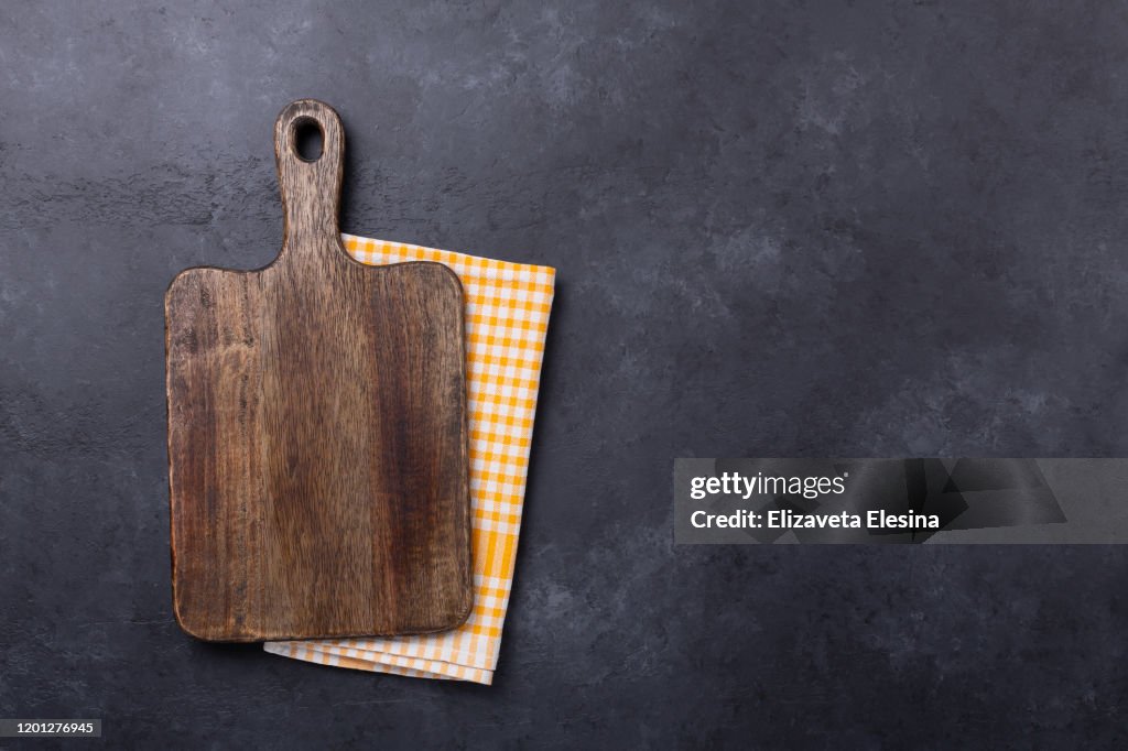 Cutting board and linen napkin on dark stone table. Copy space