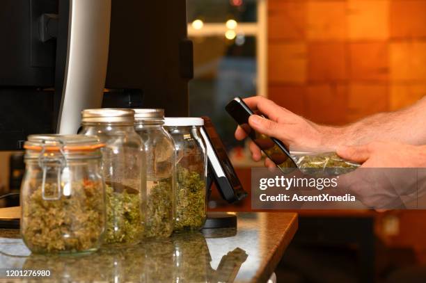 purchasing cannabis with a smart phone - cannabis dispensary stock pictures, royalty-free photos & images