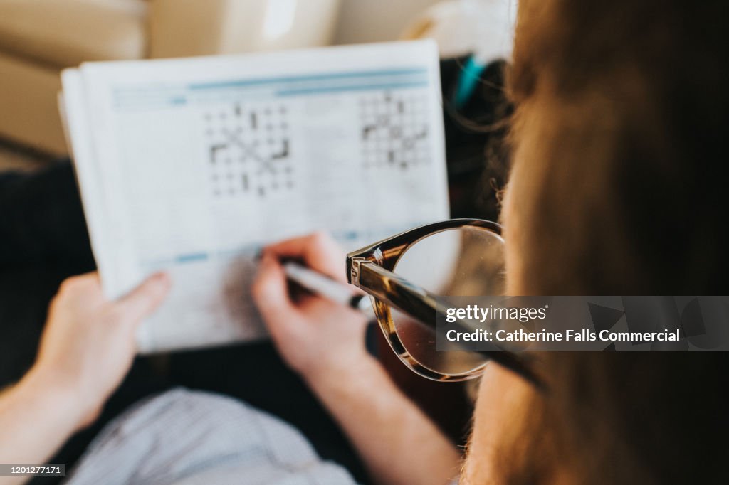 Man wearing Glasses, completing Crossword
