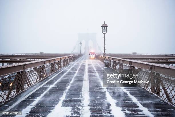 police car on an empty brooklyn bridge during a snowstorm - brooklyn bridge winter stock pictures, royalty-free photos & images