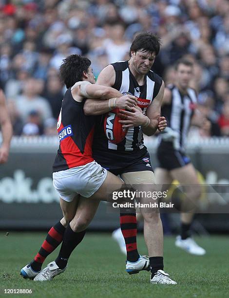 Leigh Brown of the Magpies is tackled by Angus Monfries of the Bombers during the round 19 AFL match between the Collingwood Magpies and the Essendon...