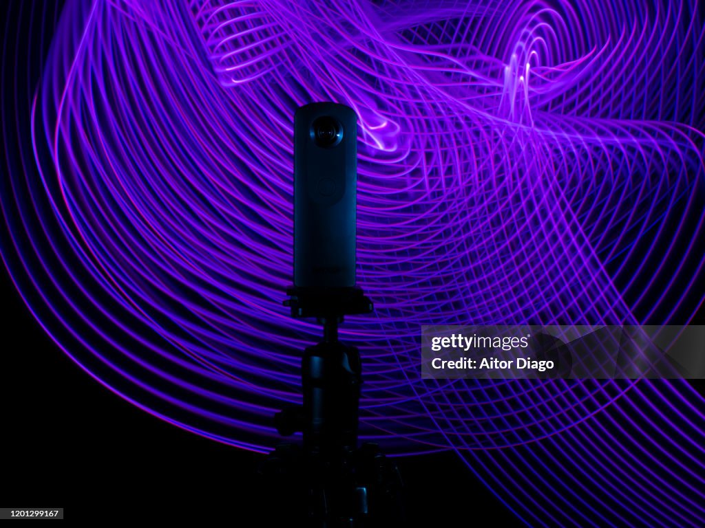 Close up of a 360º camera on a tripod with a purple futuristic interconnected background