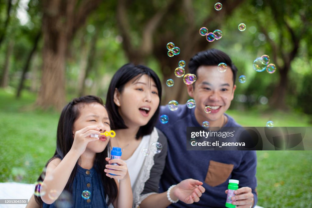 Happy Asian family are blowing soap bubbles together in park, Taipei