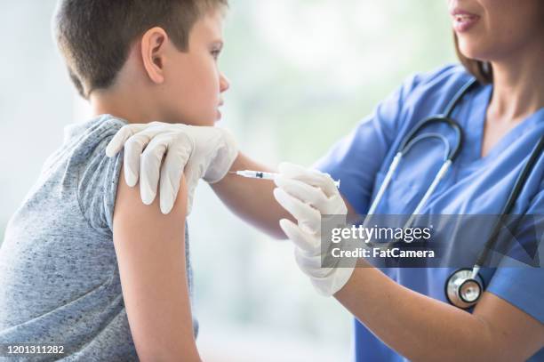 young boy receiving an immunization needle stock photo - vaccine confidence stock pictures, royalty-free photos & images