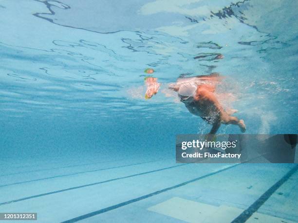 hogere mens die freestyle onderwater in een zwembad zwemt - aquatic therapy stockfoto's en -beelden
