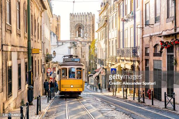 street in lisbon old town with yellow tram and lisbon cathedral in background, lisbon, portugal - lisbon stock pictures, royalty-free photos & images